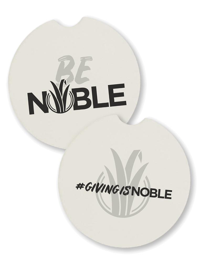 Car Coasters in car cupholder. One says 'Be Noble' and the other says '#GivingIsNoble'