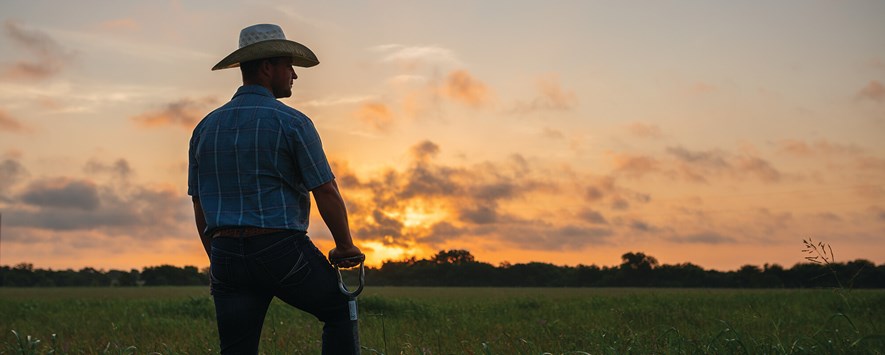 Noble Ranch Facility Manager Clark Roberts stands in pasture at sunset with shovel