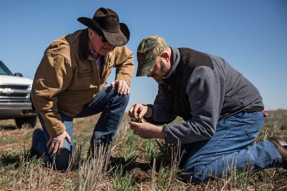 Noble consultant, Jim Johnson, inspects a clump of soil with a rancher.